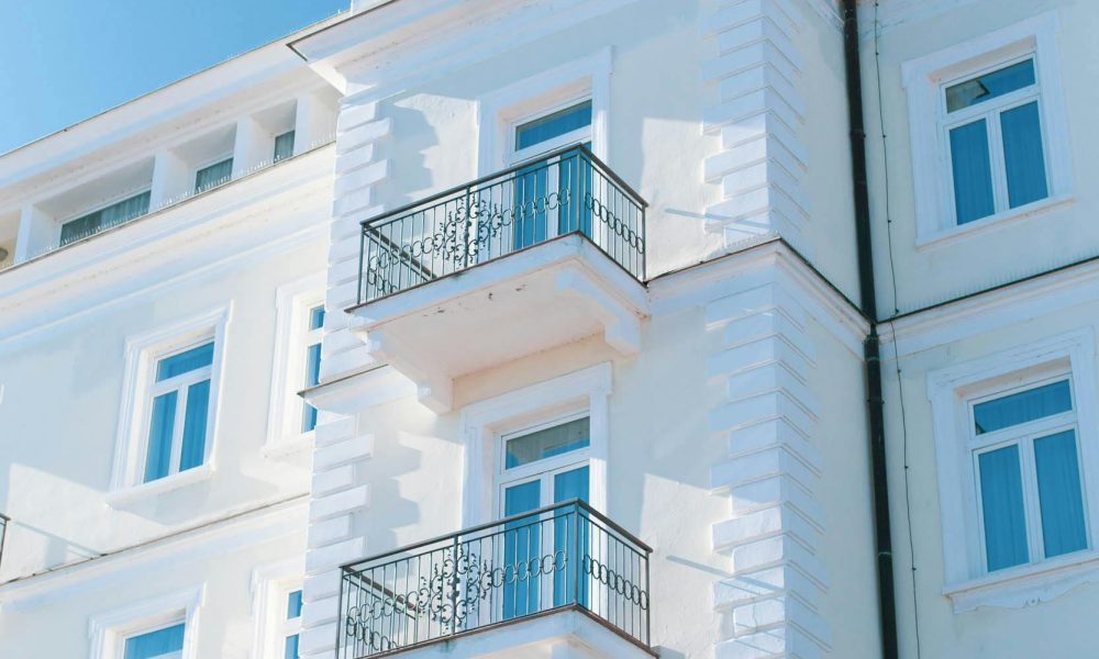 Bright white building facade with balconies against a clear blue sky in Opatija, Croatia.
