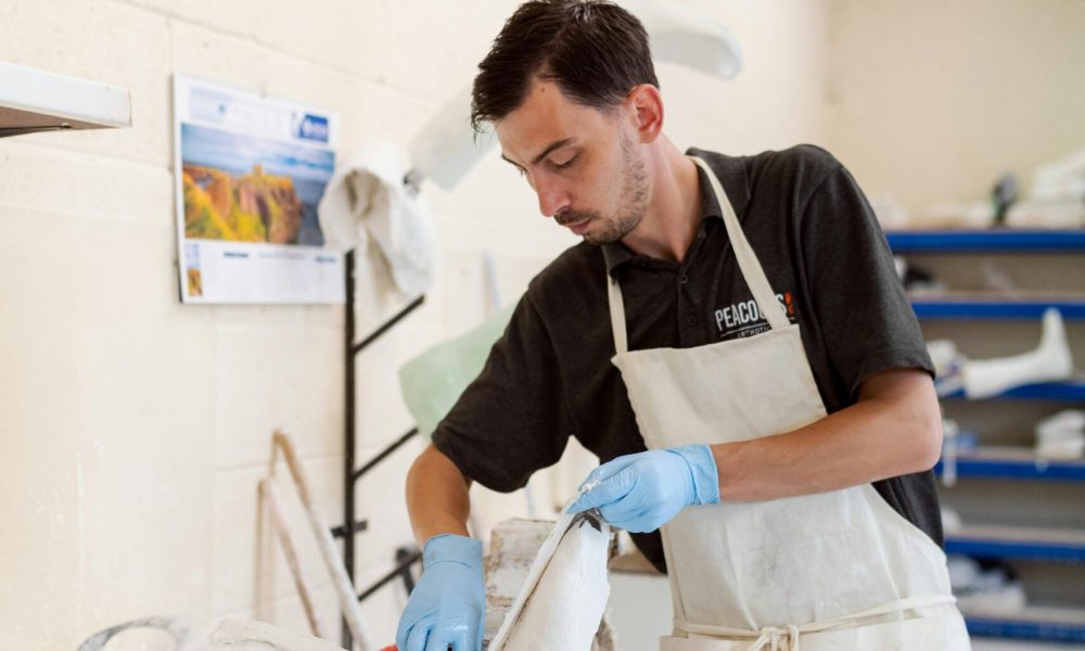 Orthotic technician skillfully crafting a custom foot brace in a well-equipped workshop.