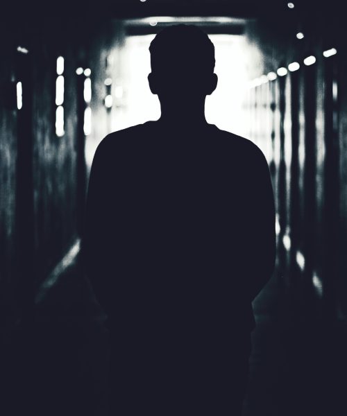 Silhouette of a person standing in a shadowy tunnel, evoking mystery.