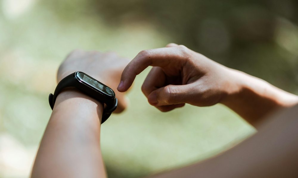 A person checking their smartwatch outside in a serene setting, focusing on technology in daily life.